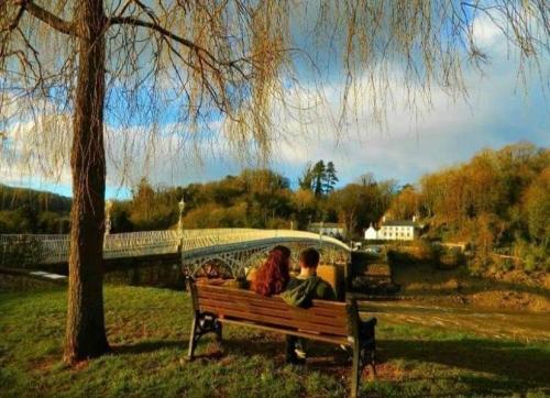 old wye bridge behind couple sat on bench